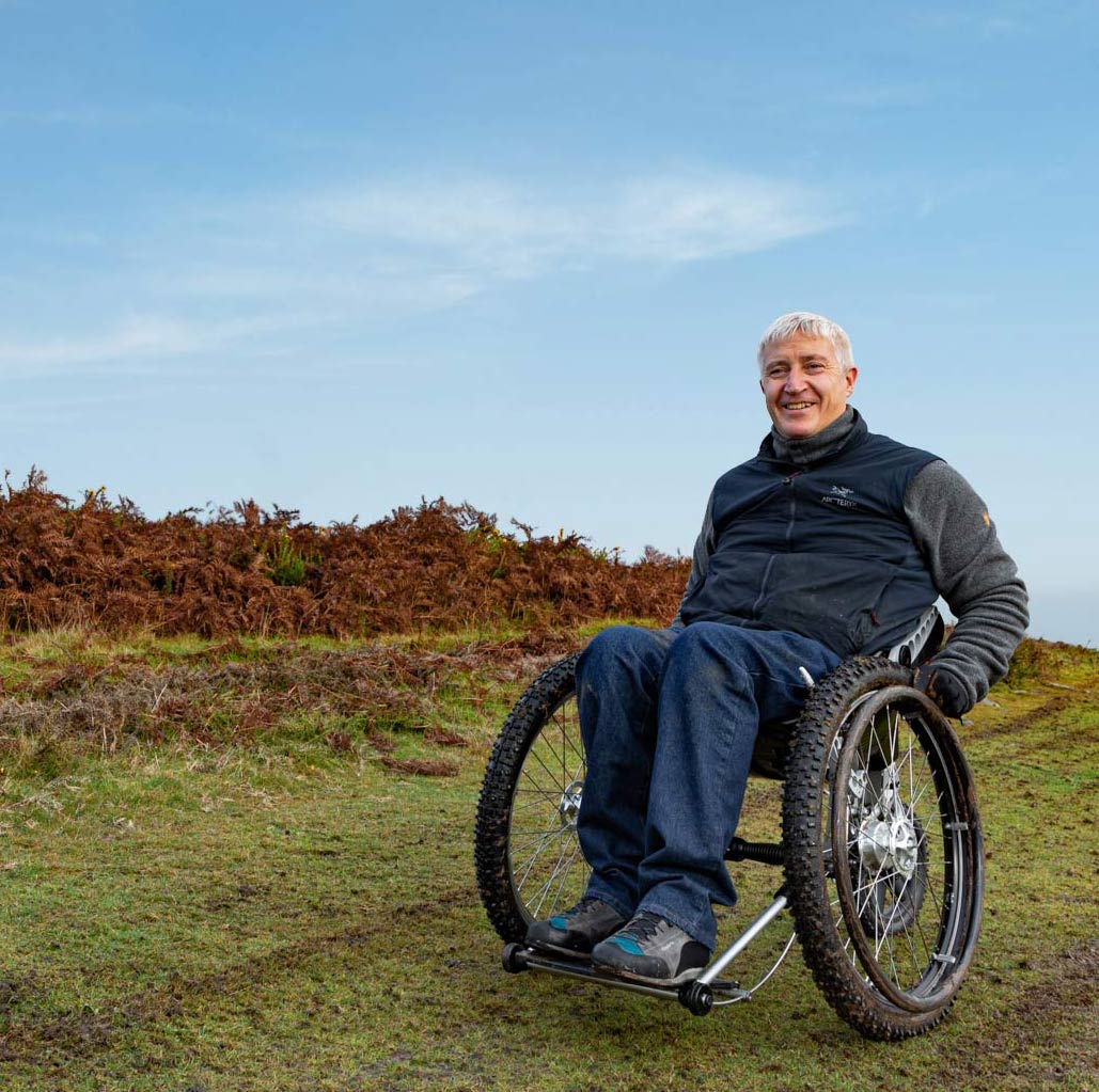 Middle aged man sitting in Trekinetic K2 all terrain manual wheelchair on muddy slope