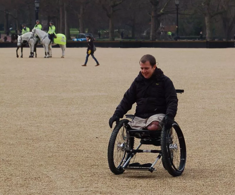 double amputee using Trekinetic K2 off road wheelchair on gravel with police horses in background
