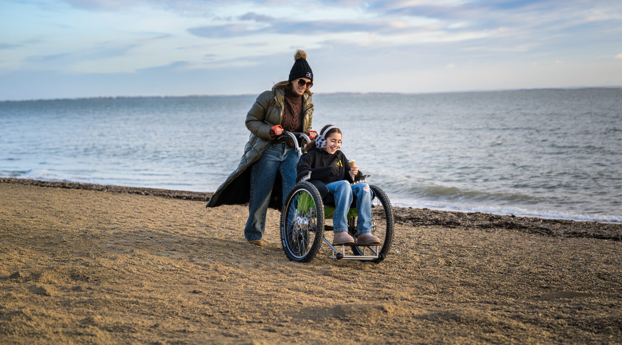 Woman Pushing her daughter on a pebble beach in a K2 Plus One