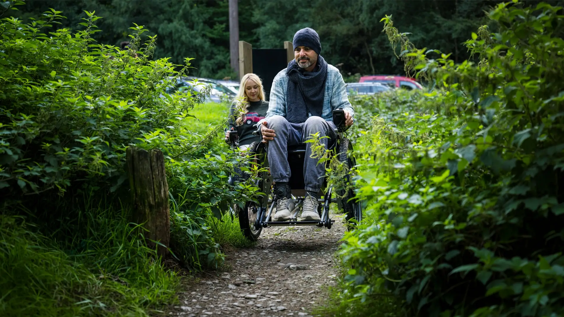 Two Trekinetic users on a gravel path through dense greenery